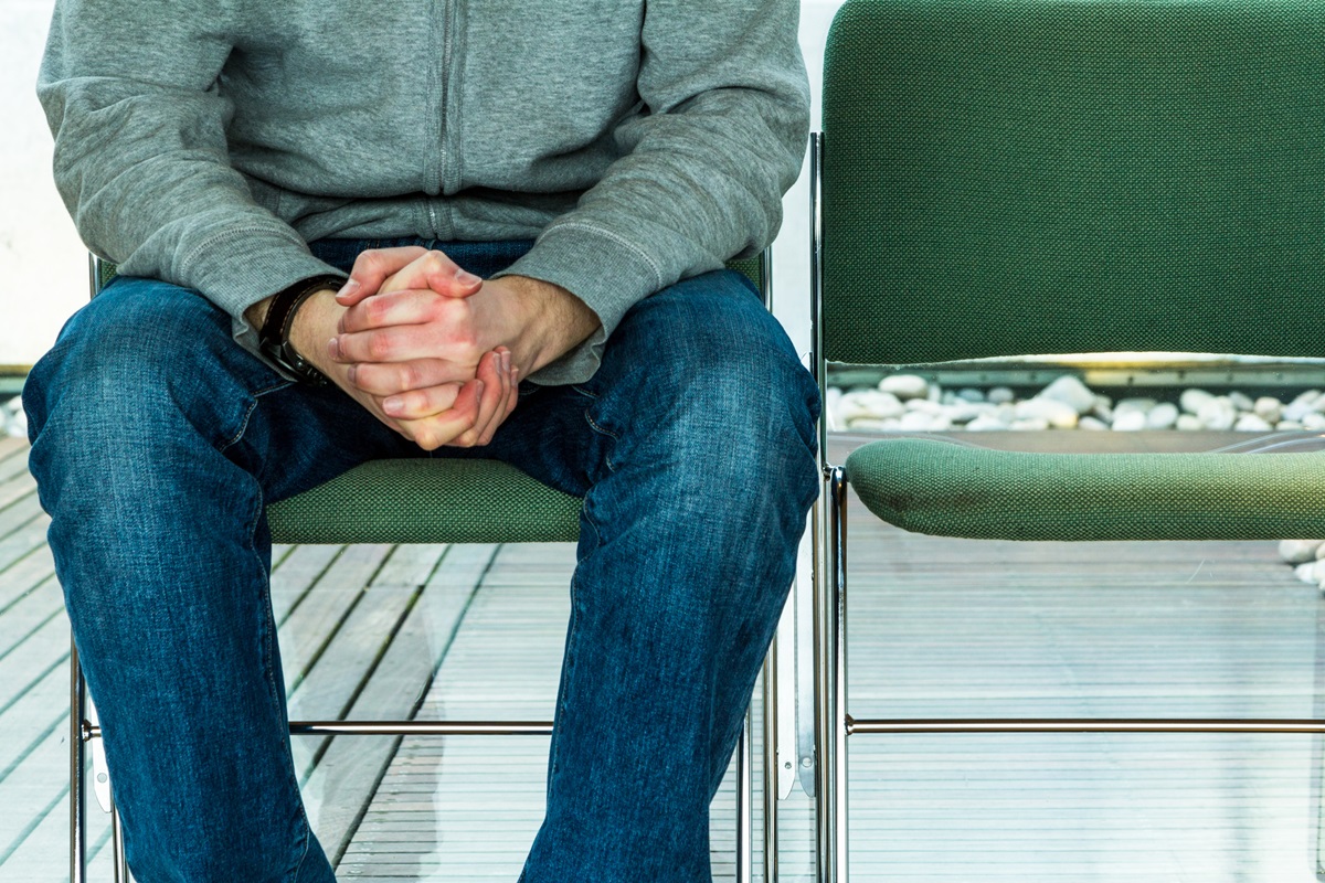 Anxious man sitting with hands clenched in waiting room